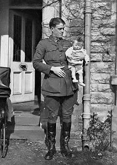 Informal full-length portrait of man in military uniform holding an infant