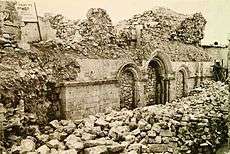 Sepia image showing remains of synagogue entrance arches blocked up with stones.