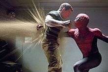 Spider-Man punches Sandman, and his fist is seen on the other side of his chest, with sand blowing through the hole