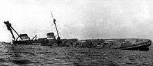 A large warship rolls onto its side