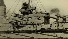 A large warship's bridge and two gun turrets