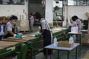 Women wearing gloves and masks on an assembly line