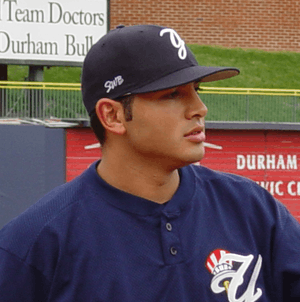 A man in a blue shirt and navy blue hat looks off to the side.