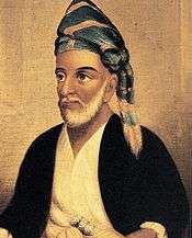A portrait of a bearded man wearing a turban or headscarf