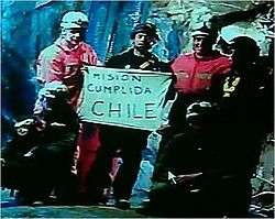 Slightly grainy color video capture image of the six rescuers displaying the famous "Mision Cumplida Chile" sign deep within San José Mine near Copiapo, Chile