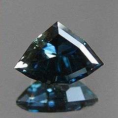 A custom shield cut sapphire from Rock Creek, Montana in deep blue with a slight green undertone or zoning.