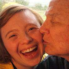 Close up of Sarah Gordy smiling while her dad gives her a peck on the cheek