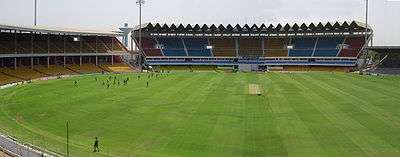 A ground with a few players practising, surrounded by empty stands.