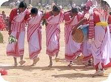 Barefoot women in pink saris dancing