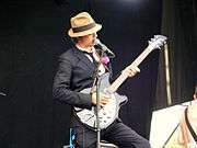 Colour photograph of Babyshambles lead singer Pete Doherty performing live in 2008. He is playing a guitar.