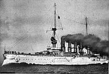 A large white warship with gray superstructure; several men are standing on the bow