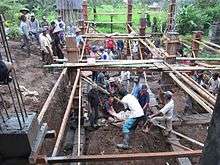 Dozens of men from an Indonesian village work on the foundation of a new building.