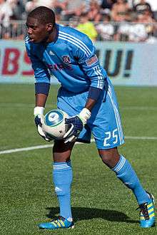 An African American male in a blue uniform is playing soccer.