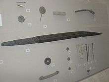 Museum display case with a long iron seax and other artefacts
