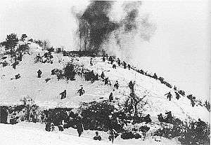 A snow covered hill with the hill top on fire and the slopes filled with charging soldiers