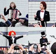 A woman with an accordion, a man in a tuxedo, a man wearing a tophat and sunglasses, and a man wearing a clown mask.