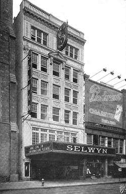 Facade of six-story office building, with theater marquee on street floor, reading "Selwyn Theatre" and "Jane Cowl in Information Please"