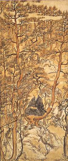 A priest seated on a branch of a pine tree in a pine tree forest.