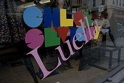 A storefront window with a large slanted "Luella" superimposed over a multi-coloured name logo that reads "CHLOË SEVIGNY".