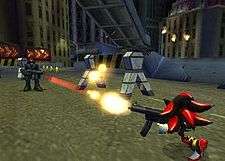The hedgehog from the cover shoots a single bullet from a machine gun-like firearm at a human soldier who attempts to do the same. The setting is a disheveled city street at night with tall buildings surrounding the area and an elevated highway overhead.
