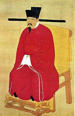 Painted image of a man sitting in a wooden chair, wearing red silk robes, black shoes, a black hat, and sporting a black mustache and goatee