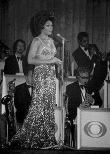 Shirley Bassey performing in front of a brass section.