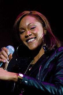 A picture of a woman wearing a black jacket and holding a microphone