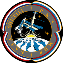 An illustration showing a space shuttle docked to a space station above a stylized version of the Earth. The Sun is rising over the Earth, and the image is surrounded by ribbon in red, white and blue. The words NASA, Shuttle, РКА and Мир are written around the image.