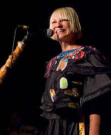 A picture of a blonde haired woman, smiling while performing