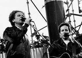 Two men singing into microphones, in a low-angle close-up, black-and-white