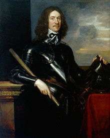 A portrait of a man dressed in black armour.  He has long brown hair down to his shoulders and a thin moustache and beard.  His left hand his holding a helmet which is resting on a pedestal.  His right hand his holding a small pole or scroll