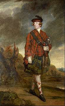 A man wearing a black hat, a red plaid shirt and socks, a green plaid kilt, and black shoes with gold buckles, carrying a satchel with its strap across his chest