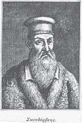 A portrait of a male with a long beard wearing a hat and a fur-collared coat