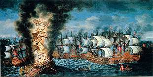 A colorful oil painting showing a large group of sailing warships engaged in battle. In the foreground to the left, a very large ship flying a Swedish flag is listing heavily and a huge explosion is shattering her structure and throwing men and equipment upwards in together with flames and black smoke