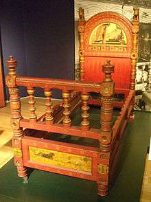 Photograph of a bed showing paintings on the headboard and the foot of the bedframe