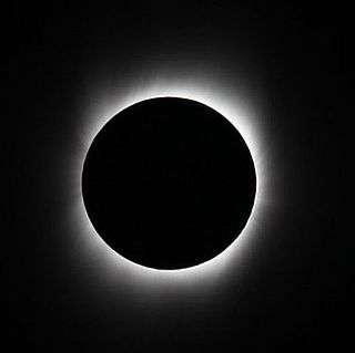 A black circle outlined in hazy streaks of white emanating from the circle to the edges of the image all on a solid black background