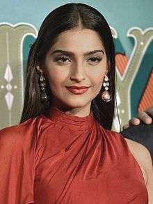 Kapoor standing in a red dress.