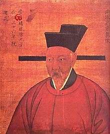 A painting of an older man with a white mustache, wearing red robes and a square cut cap.