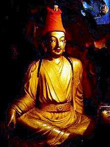 Gold-colored statue of Songtsen Gampo wearing a red cloth hat