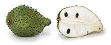 soursop fruit, whole and in section. It is green with scales has white flesh and black seeds
