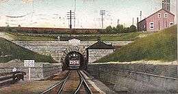 alt=A postcard with a frontal view of a train emerging from a tunnel