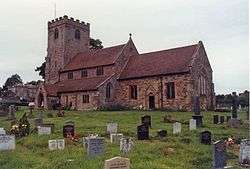 Sandstone church with square tower standing in graveyard.