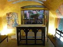 View of the Children's Chapel from its doorway with its altar in the centre and the murals on gold walls