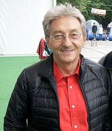 A photo of Allan Starski wearing a black bubble vest over a red collared shirt.