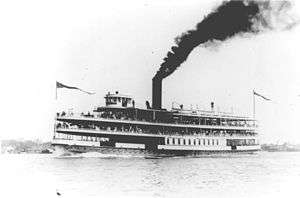 A ship on the water, the stack belching a column of black smoke.