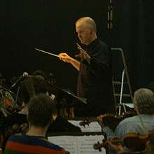 Middle-aged man conducting orchestra in recording studio