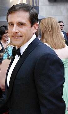 A man with black hair, Steve Carell, is standing in a tux. He is looking towards, but not directly at, the camera.
