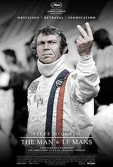 Image of actor Steve McQueen in road racing attire holding up two fingers