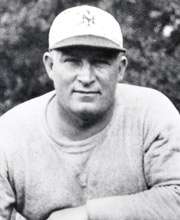 Posed black and white photograph of Owens wearing a grey sweatshirt and a white New York Giants baseball cap