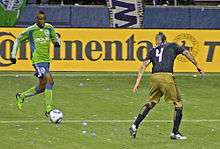 Zakuani dribbles towards an opposing player during a match